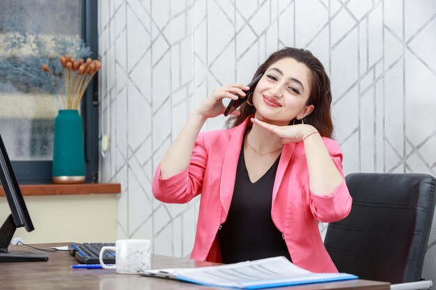 Cheerful young lady talking on the phone and smiling to the camera