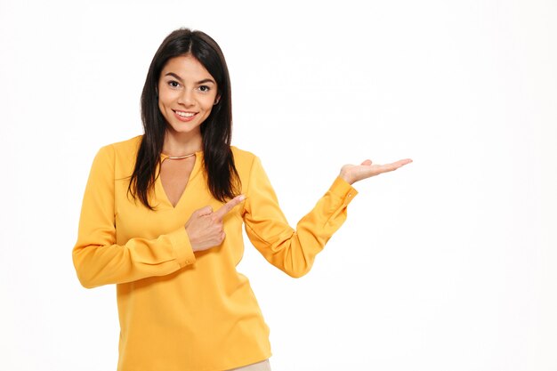 Cheerful young lady in yellow shirt holding copyspace in hand.