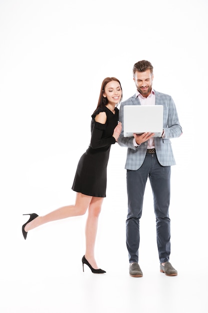 Cheerful young loving couple using laptop computer.