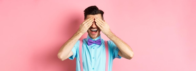 Free photo cheerful young man celebrating waiting for surprise with closed eyes and happy smile standing joyful