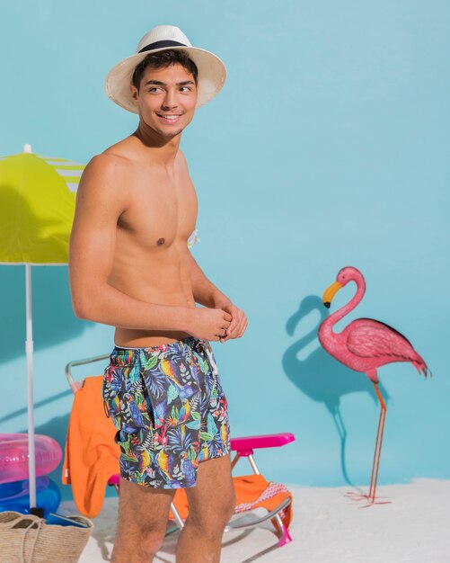Cheerful young man in hat on beach in studio