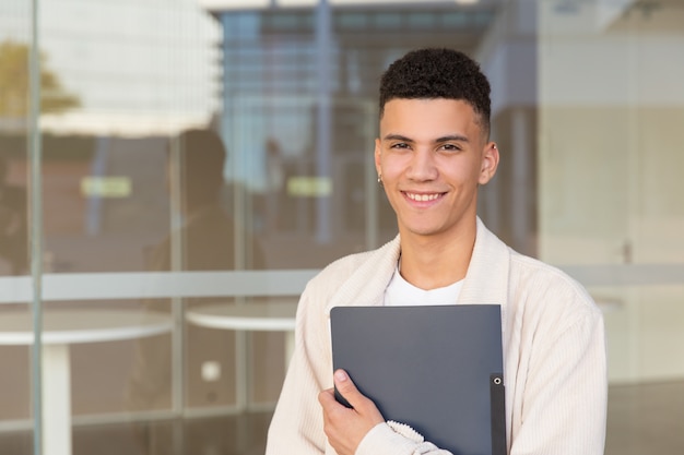Cheerful young man holding folder outdoor