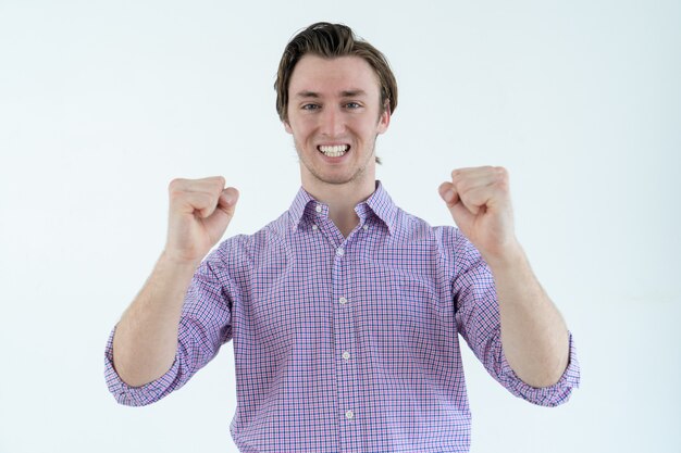 Cheerful young man looking at camera and pumping fists. Success concept.