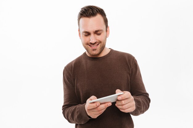 Cheerful young man play games by mobile phone