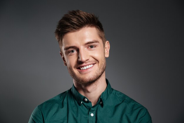 Cheerful young man posing isolated over grey