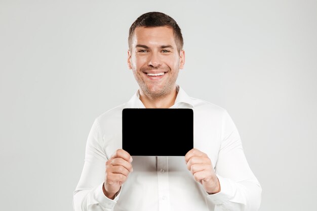 Cheerful young man showing display of tablet computer.