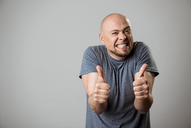 Cheerful young man smiling, showing okay over beige wall