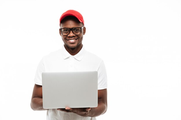 Cheerful young man wearing cap using laptop computer