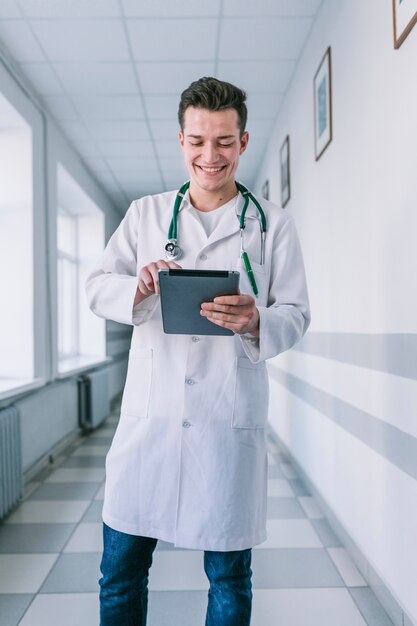 Cheerful young medic man using tablet