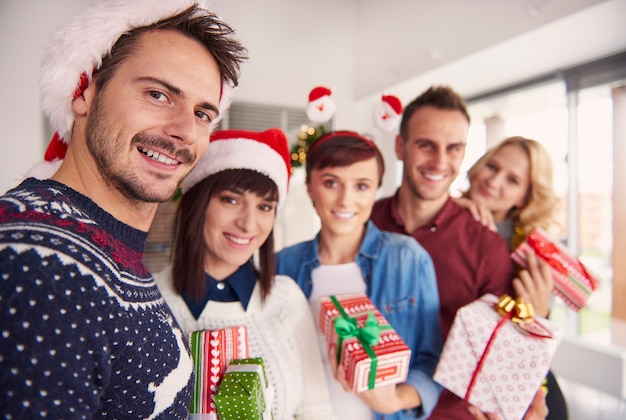 Cheerful young people holding Christmas gifts