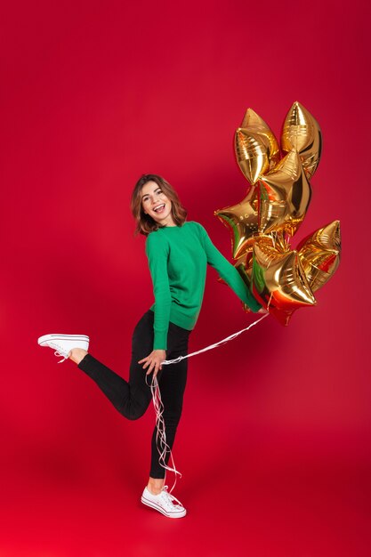 Cheerful young pretty woman holding balloons.