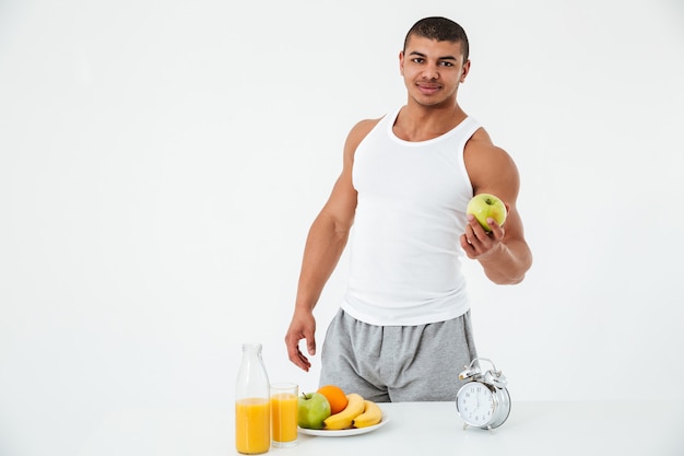 Free photo cheerful young sportsman holding apple.