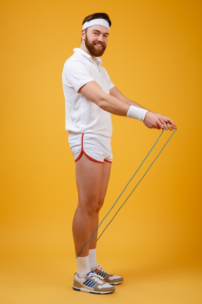 Free photo cheerful young sportsman holding skipping rope