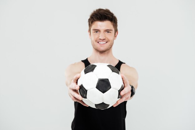Веселый молодой спортсмен с мячом для ног