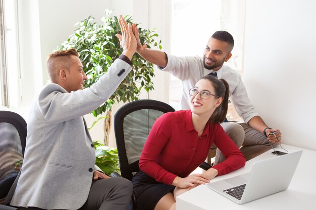 Cheerful young startuppers giving high five