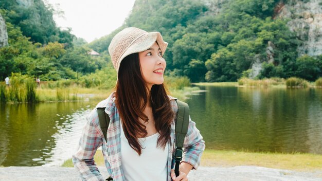 Дама жизнерадостного молодого путешественника азиатская с рюкзаком идя на озеро горы. Корейская девушка наслаждается своим праздником приключений, чувствуя счастливую свободу. Образ жизни путешествовать и отдыхать в свободное время концепции.