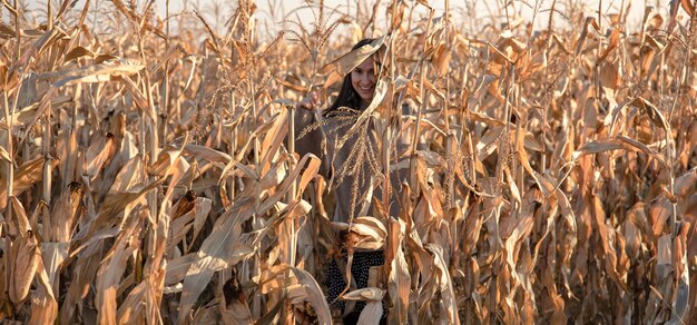 Веселая молодая женщина на кукурузном поле осенью.