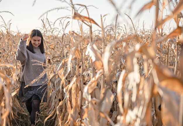 秋のトウモロコシ畑の陽気な若い女性