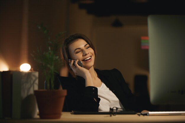 Cheerful young woman designer talking by phone.