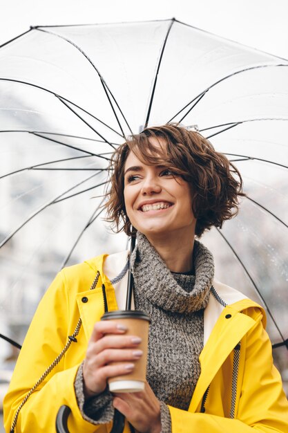 Cheerful young woman dressed in raincoat