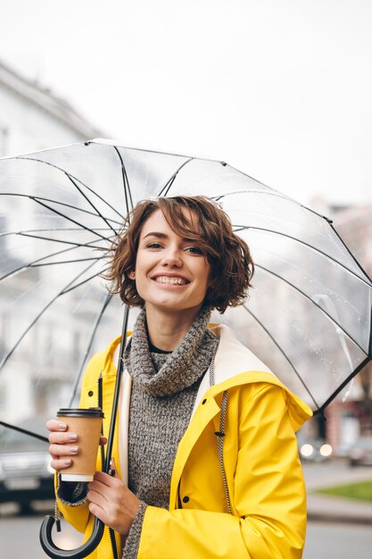 Cheerful young woman dressed in raincoat