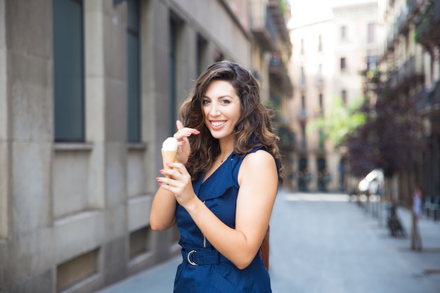 Cheerful young woman eating ice cream outdoors