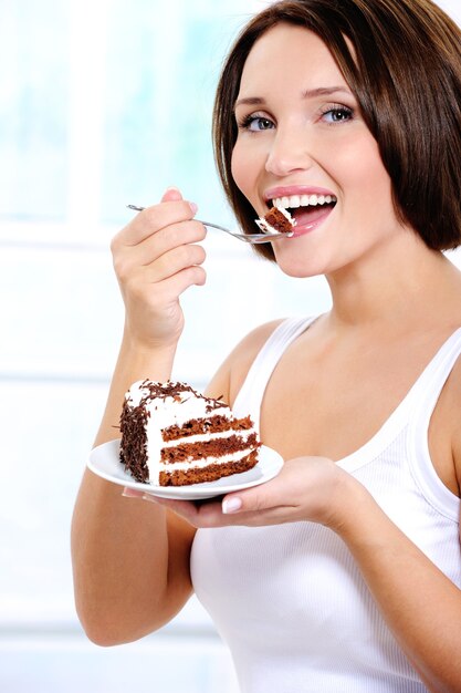cheerful young woman eats a sweet cake
