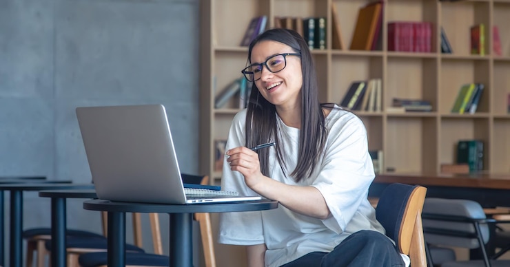 Free Photo cheerful young woman in glasses in front of a laptop