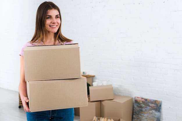 Веселая молодая женщина держит картонные коробки в своем новом доме