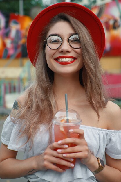치아를 보여주는 웃고있는 동안 음료를 들고 쾌활 한 젊은 여자