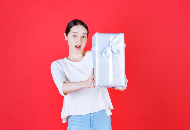 Cheerful young woman holding gift box