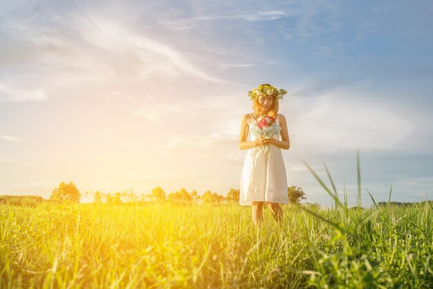 牧草地で彼女の花束を保持朗らか若い女性