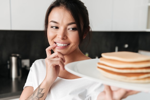 パンケーキを保持している陽気な若い女性。