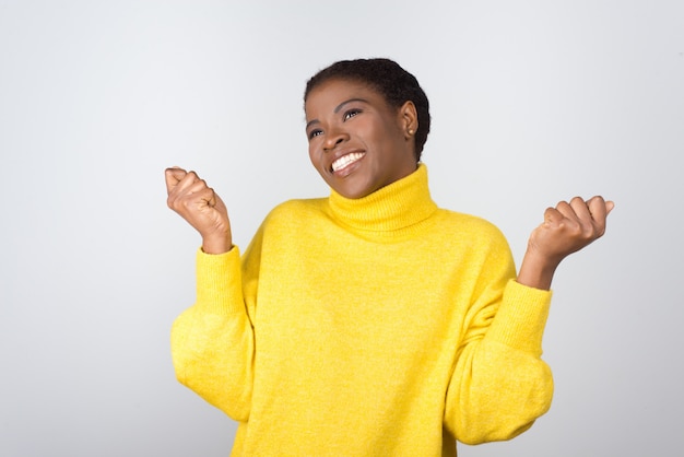 Cheerful young woman raising fists