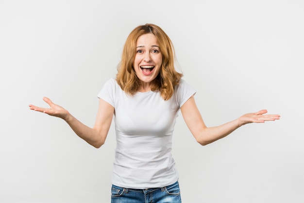Cheerful young woman shrugging against white background