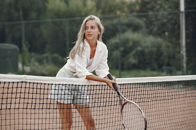 Tシャツを着た元気な若い女性。テニスラケットとボールを保持している女性。