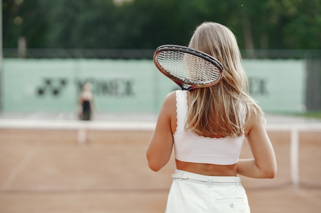 T- 셔츠에 쾌활 한 젊은 여자. 테니스 라켓과 공을 들고 여자입니다.