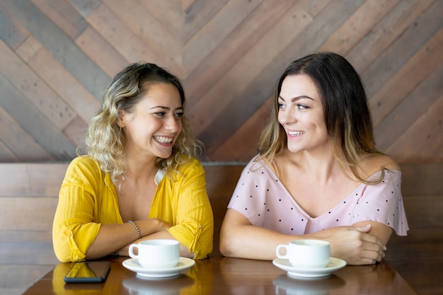 カフェで彼女の友人に知らせる朗らかな若い女性