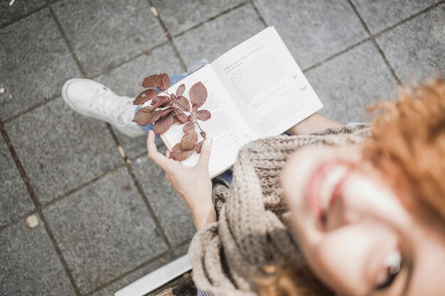 本と紅葉のある朗らかな若い女性