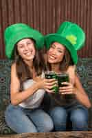 Free photo cheerful young women hugging and clanging glasses of drink on settee