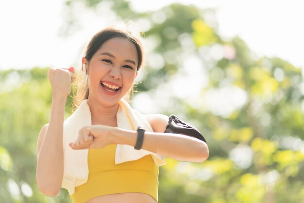 Азиатская улыбающаяся женщина-спортсменка на утренней пробежке радуется победе