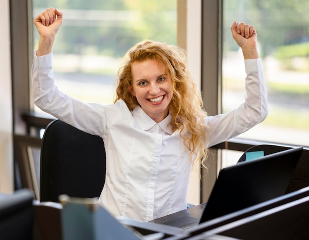 Free photo cheering businesswoman at her workplace