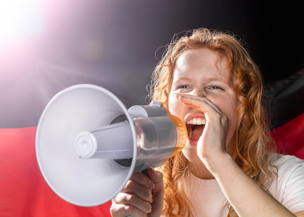 Free photo cheering woman speaking in megaphone with german flag