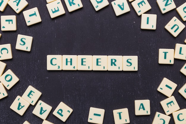 Free photo cheers scrabble letters over black background