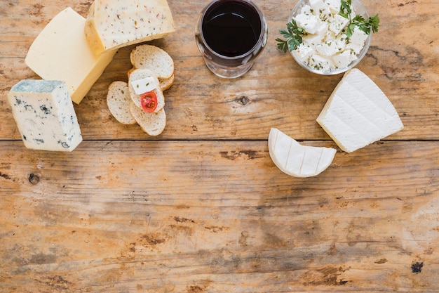 Cheese blocks with red wine and bread on wooden desk