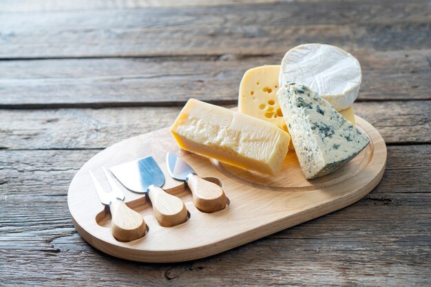 カマンベール​チーズ​、​パルメザンチーズ​、​マースダムチーズ​の​チーズ​ボード​。​素朴な​食べ物​の​背景​。