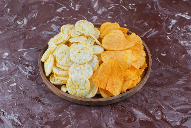 Бесплатное фото Сырные чипсы и картофельные чипсы в тарелке на мраморной поверхности