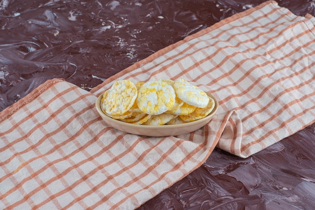 Бесплатное фото Сырные чипсы в тарелке, на кухонном полотенце, на мраморном столе.