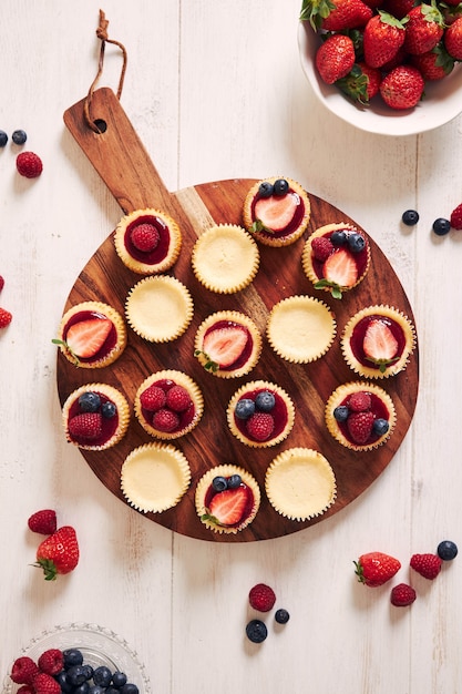 Cheese cupcakes with fruit jelly and fruits on a wooden plate