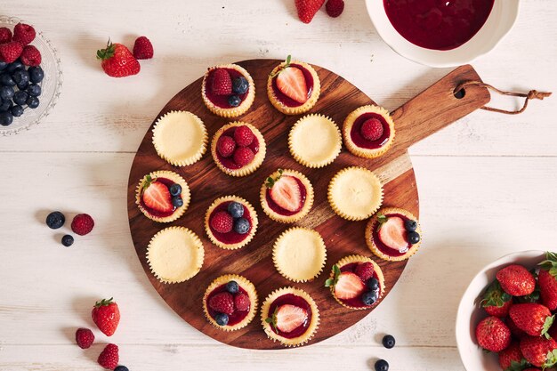 Cheese cupcakes with fruit jelly and fruits on a wooden plate
